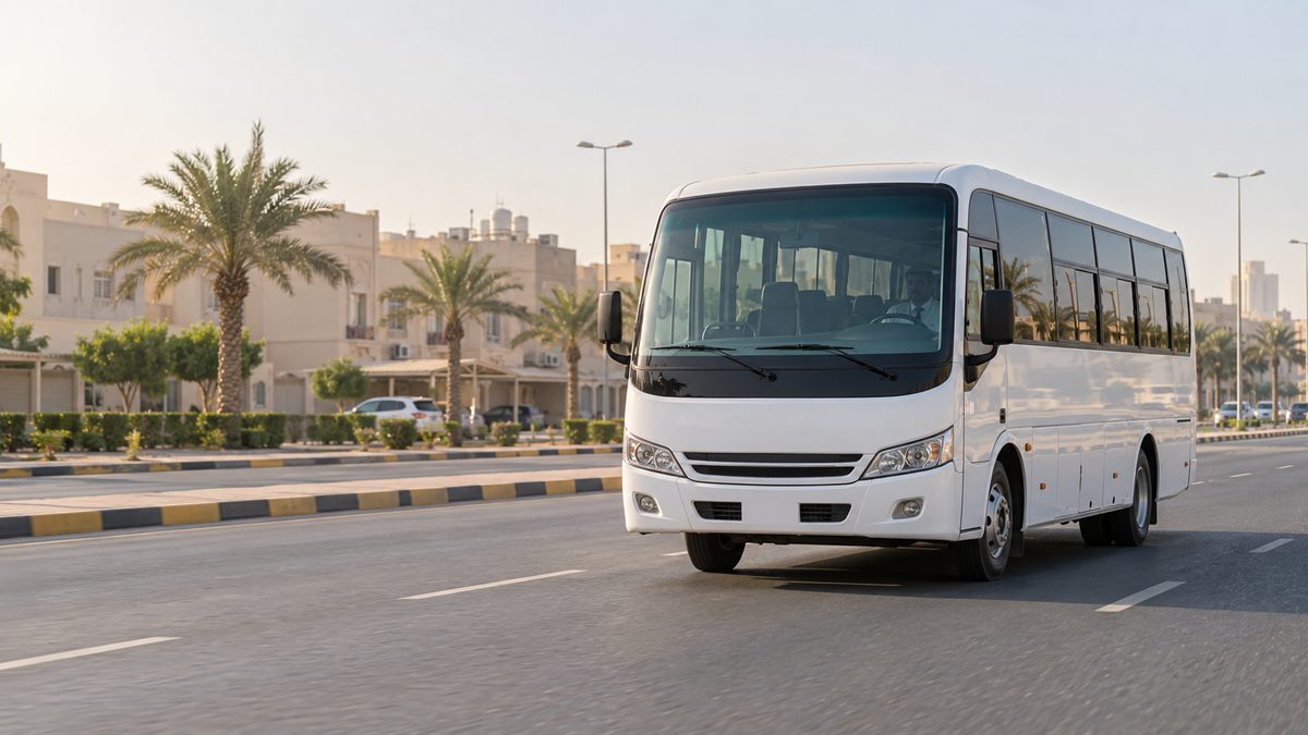 A white bus travelling along a palm-lined road in Kuwait.
