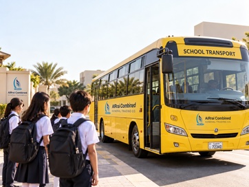 Students with backpacks wait at the kerb as a yellow AlRrai Combined school transport bus arrives at school.